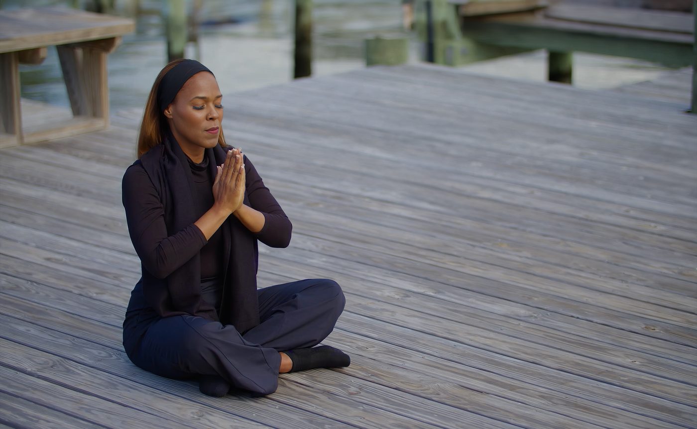 Carmen Kennedy seated in prayer position on the dock, eyes closed