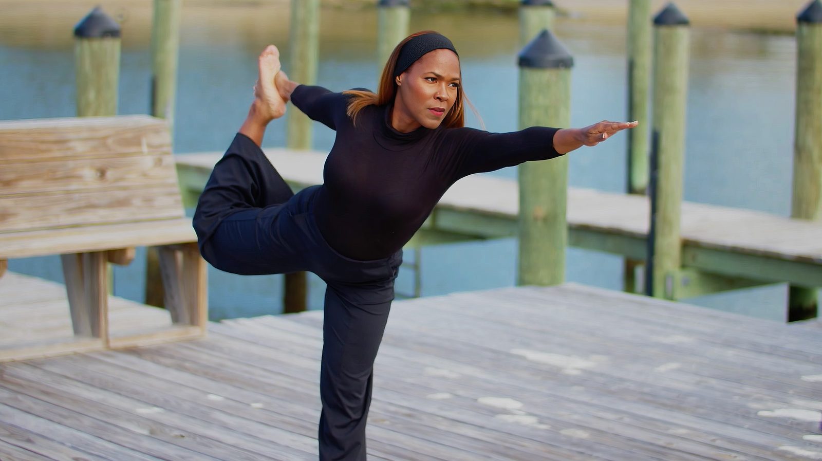 Carmen Kennedy holding a dancer yoga pose on the dock at the James River
